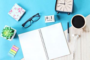 top-view-or-flat-lay-of-open-notebook-paper-accessories-cube-calendar-and-coffee-cup-on-wooden-background-ready-for-adding-or-mock-up